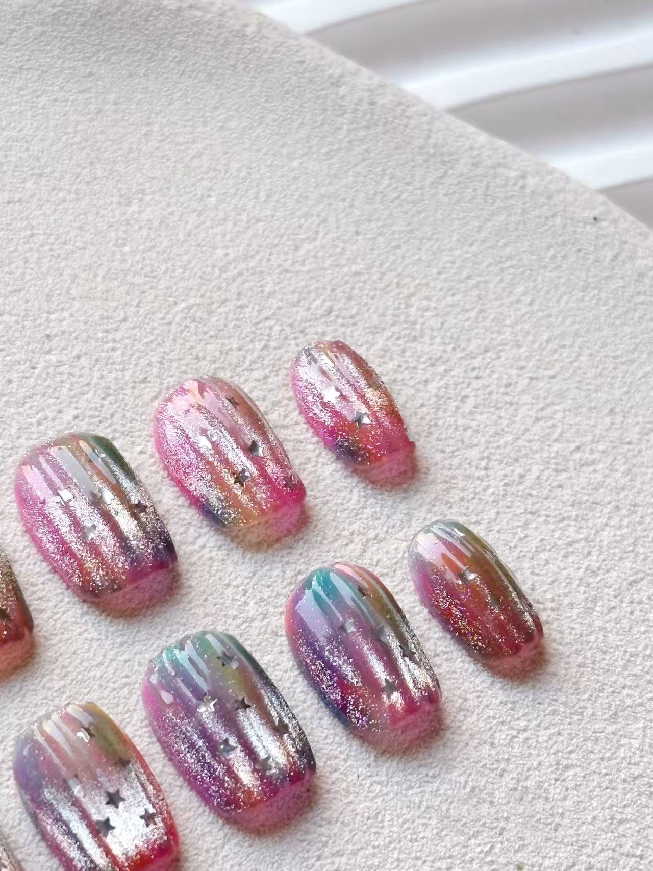 A macro view of the cosmic star press-on nail set, showing glitter detail and multi-colored bases on the nails.