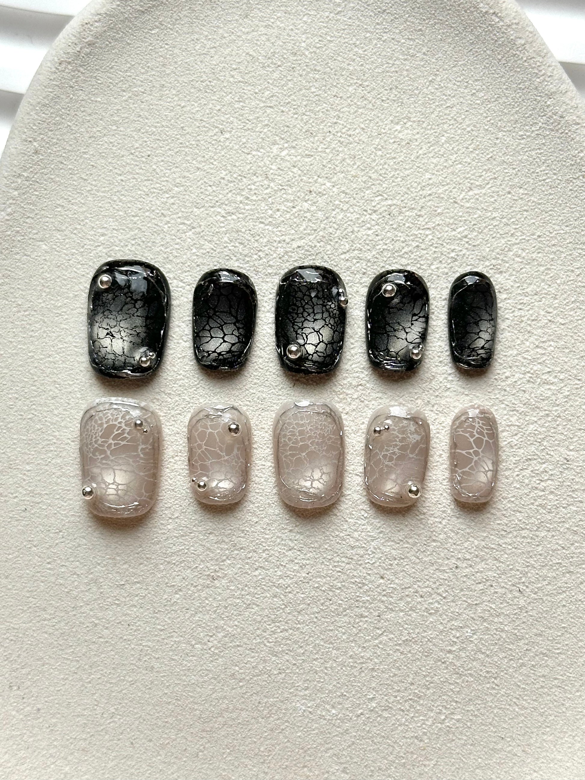 A set of 10 press-on nails featuring black and nude spider web crackle designs with 3D silver beads