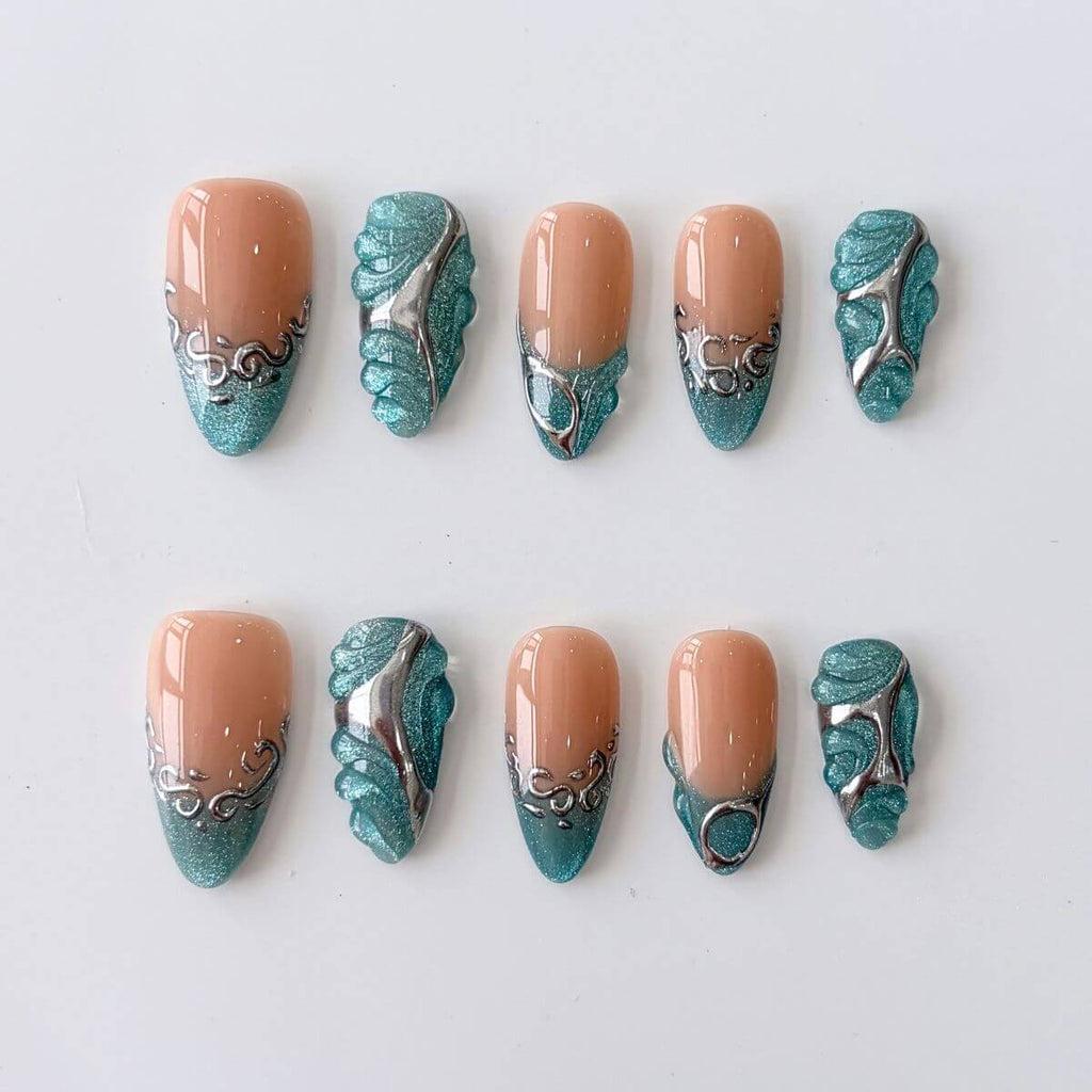 Flatlay of Blue Mercury press on nails in long almond shape. Features a milky blue-white base and 3D silver chrome liquid metal sigils for a DIY manicure.