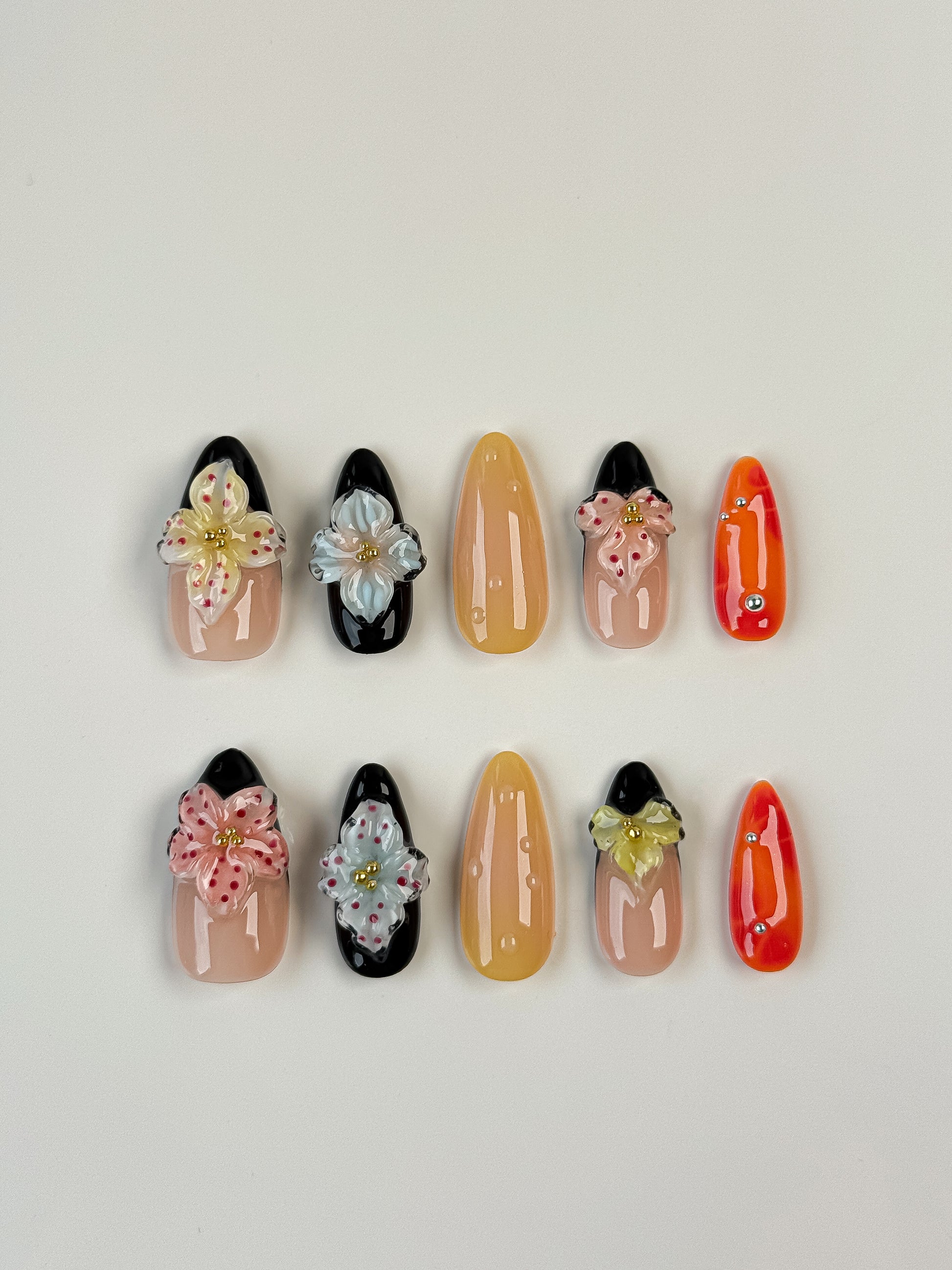Almond-shaped tropical press-on nails with 3D floral designs in black, nude, orange and yellow colors – summer nail art set