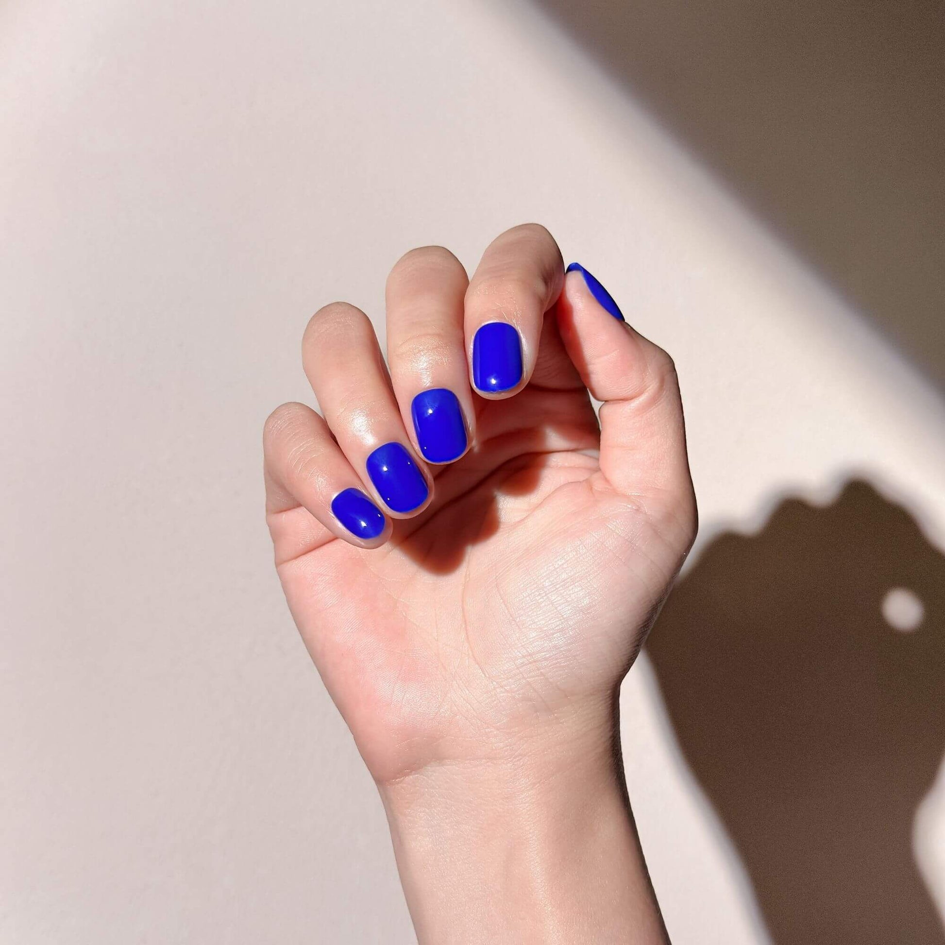 Close-up of a hand wearing the short cobalt blue glossy nails
