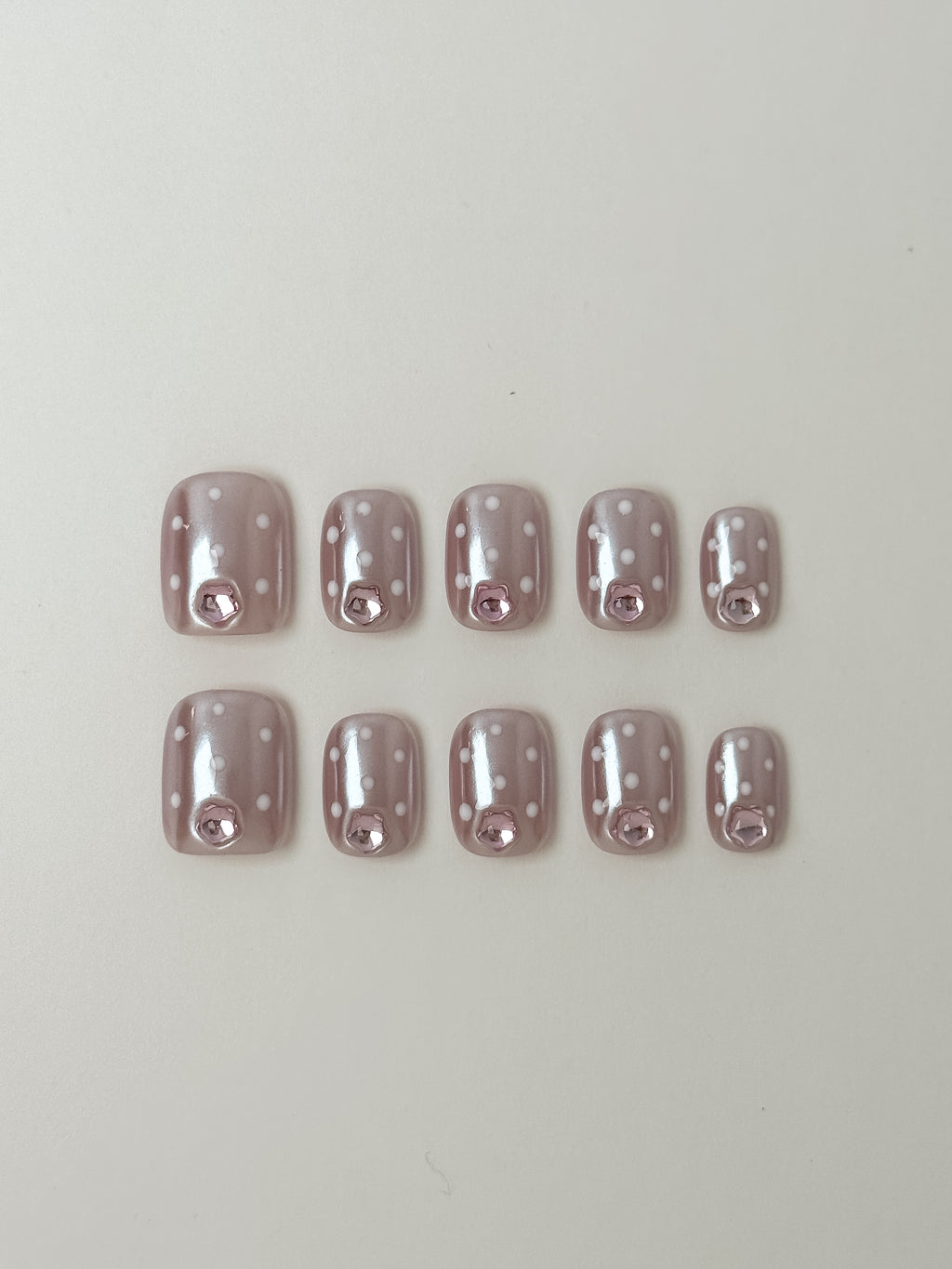 Blush shimmer press-on nails with white polka dots and pink gem on short square shape by Justmee