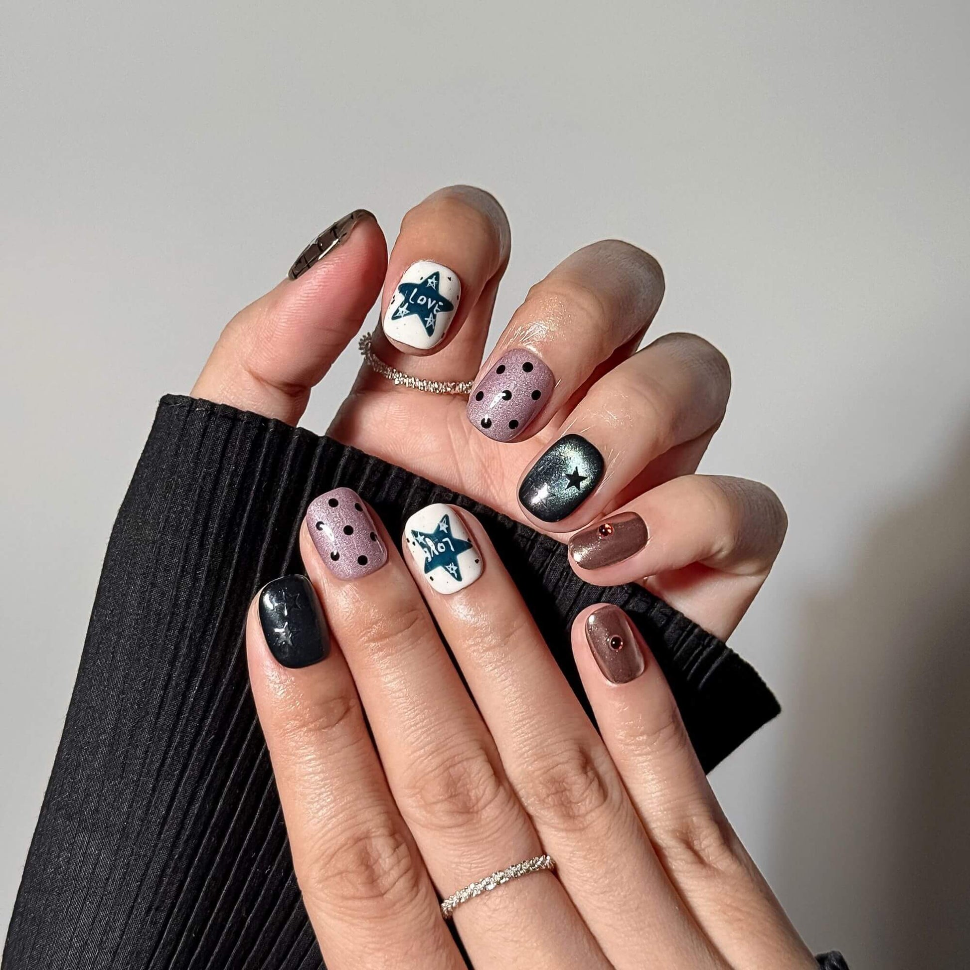 Professionelle Lifestyle-Fotografie beider Hände mit den handgefertigten Celestial Grunge Kunstnägeln, kombiniert mit minimalistischen Silberringen für einen trendigen Y2K-Look.