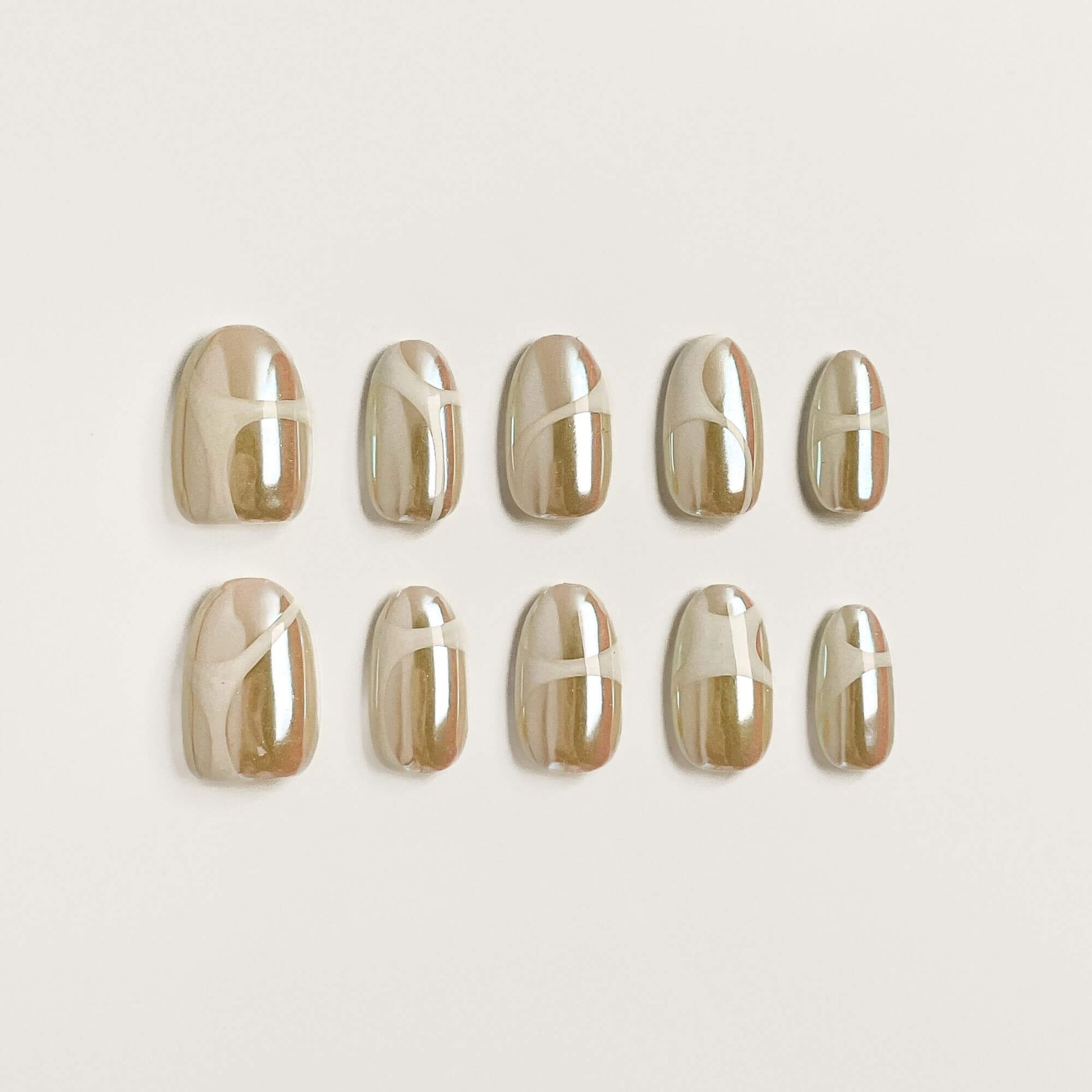 Ein 10er-Set handgefertigte Champagne Glaze Press-on Nails mit weißem abstraktem Wirbel-Design auf Perlmutt-Chrome.