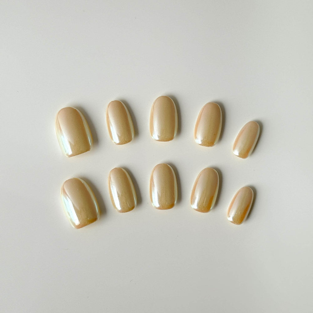 Ein 10er-Set handgefertigte Champagne Glaze Press-on Nails mit Perlmutt-Chrome-Finish in kurze ovaler Form.