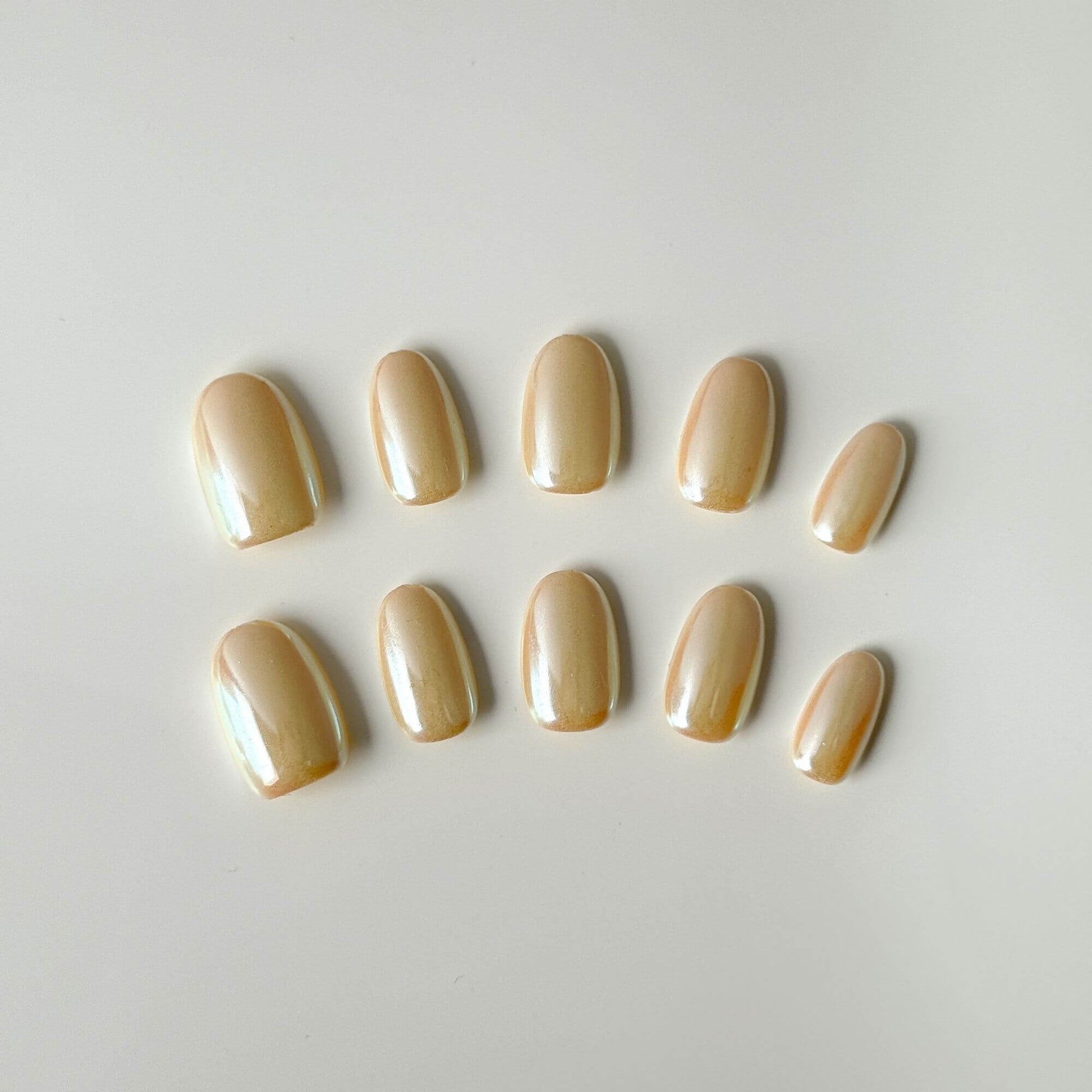 Ein 10er-Set handgefertigte Champagne Glaze Press-on Nails mit Perlmutt-Chrome-Finish in kurze ovaler Form.