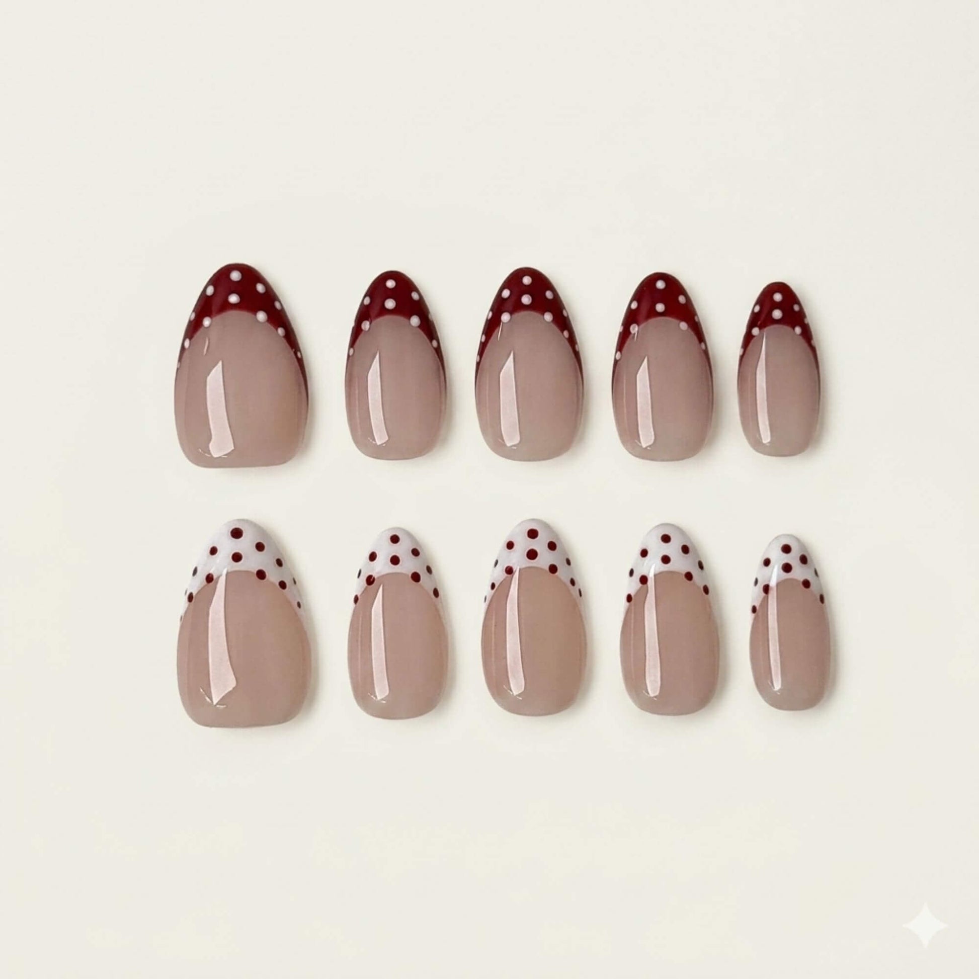 Eine Produktübersicht von 10 handgefertigten mandelförmigen Kunstnägeln mit gemischten rot und weiß gepunkteten French-Tip-Designs aus der Cherry Mix Kollektion.