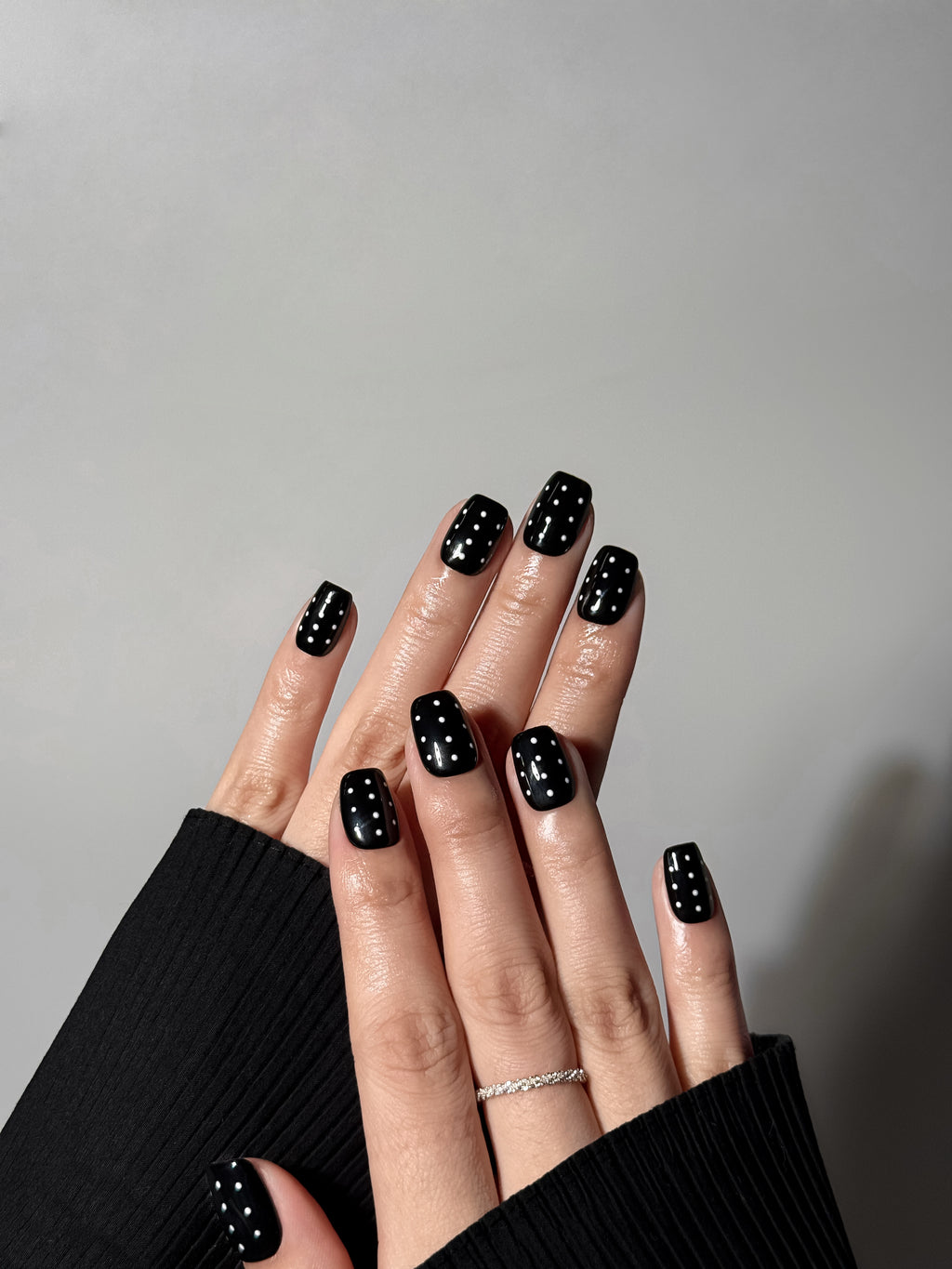 Glossy black short square press-on nails with white polka dot pattern. Reusable.