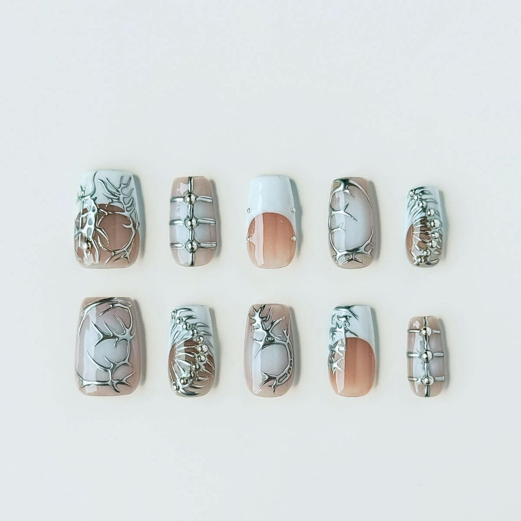 Flatlay of The Starry Chrome press on nails in long almond shape, featuring milky white gel and silver metallic star art for a celestial DIY manicure.