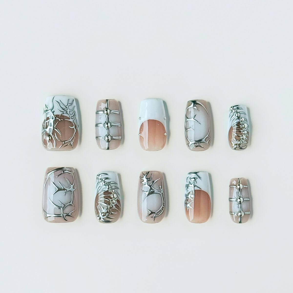 Flatlay of The Starry Chrome press on nails in long almond shape, featuring milky white gel and silver metallic star art for a celestial DIY manicure.