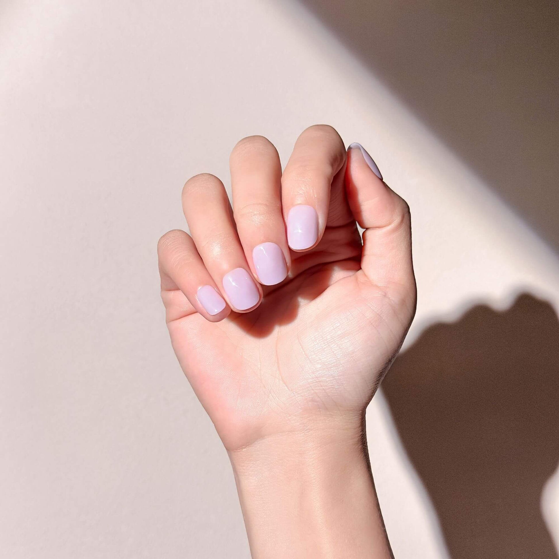 A hand wearing short square oval lavender press-on nails for a soft spring look.