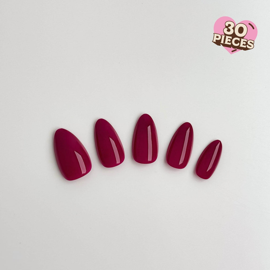 Five glossy magenta press-on nails in a medium almond shape.