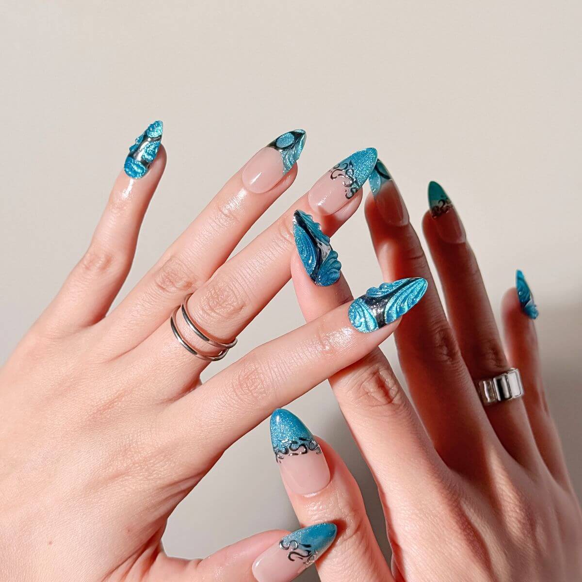 Nahaufnahme von Blue Mercury künstlichen Nägeln an der Hand. Zeigt reflektierende Chrome-Sterne und das eisblaue Gel-Finish dieser hochwertigen Kunstnägel.