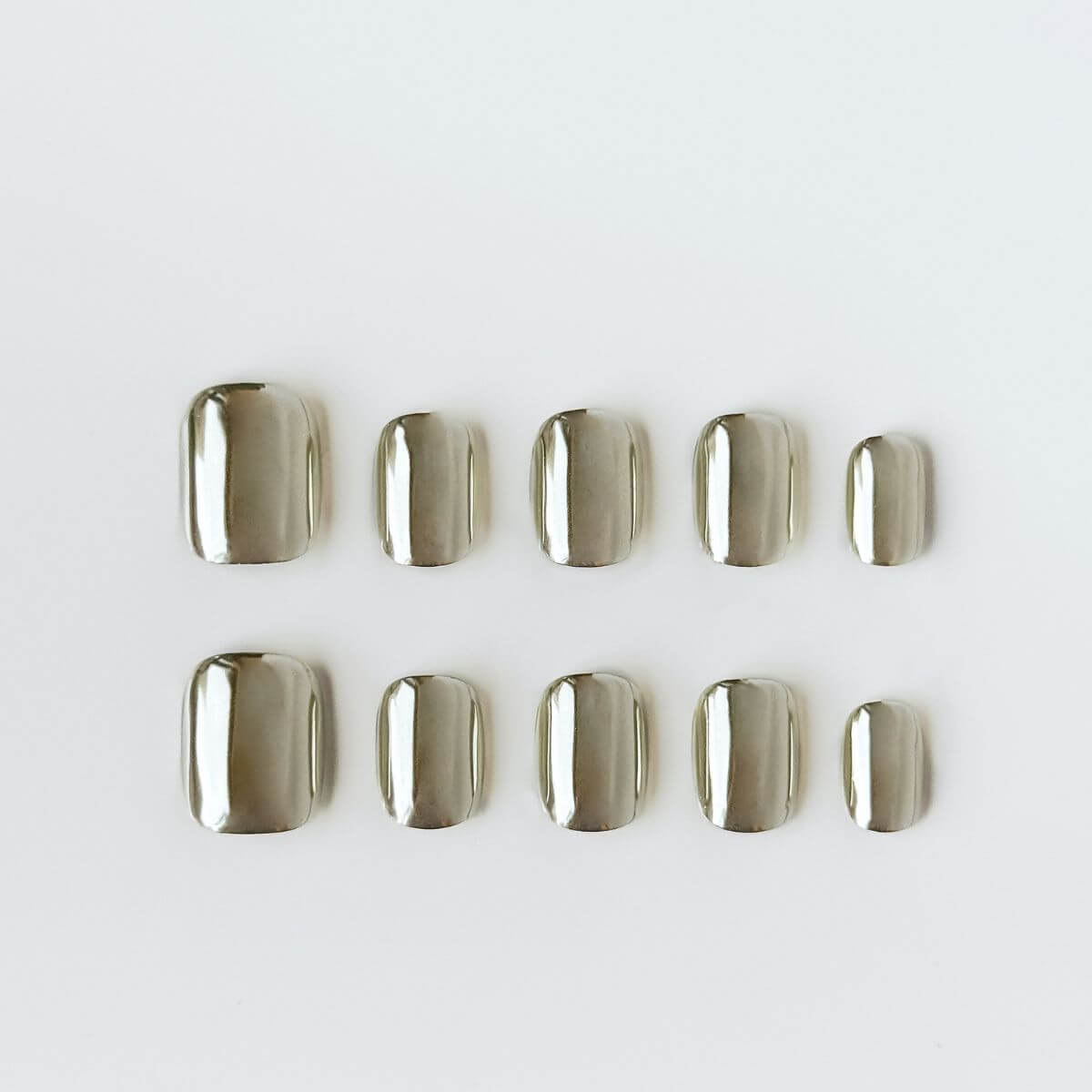 Flatlay der justmee Modern Minimalist Kunstnägel. Kurze, eckige Form mit silbernem Spiegel-Chrome-Finish für eine cleane, modische Maniküre zum Selbermachen.