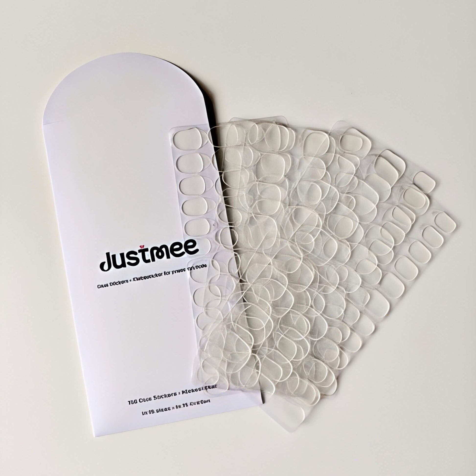 Nahaufnahme der Justmee-Verpackung für 150 transparente Klebesticker in 15 verschiedenen Größen, speziell entwickelt für die einfache Anwendung von Press-on-Nägeln.