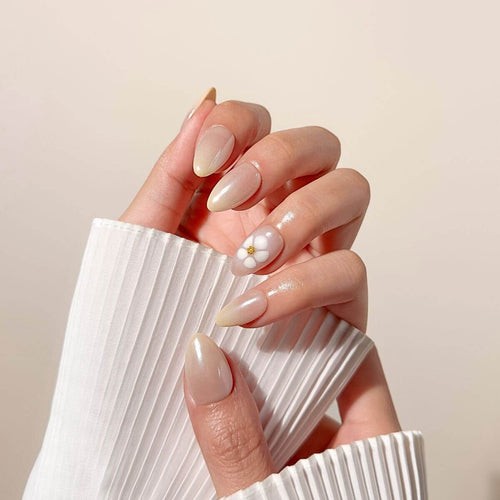 Hand eines Modells mit zarten Goldringen präsentiert die Blossom Glaze Maniküre und betont den zarten, irisierenden rosa Schimmer und die eleganten Blüten-Akzente.