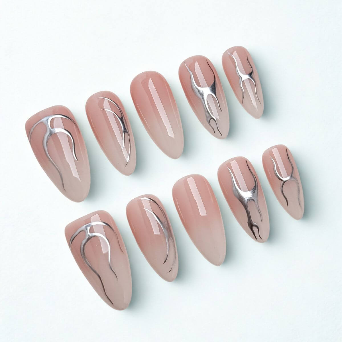 Flatlay von 10 justmee Kunstnägeln mit Nude-Ombre-Verlauf und feiner 3D-Chrome-Nailart im Cyber-Stil. Perfekte künstliche Nägel zum Aufkleben in lange Mandelform.