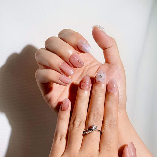 Elegantes Lifestyle-Foto von Händen mit nude-rosa Marmornägeln und einem Schmetterlingsring, ideal für einen femininen und gepflegten Look.