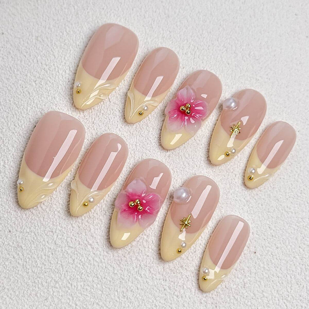 A product overview flat lay of the Vanilla Blossom artificial nail set, displaying 10 sample nails with pastel yellow French tips, 3D pink cherry blossoms, pearls, and gold stars.
