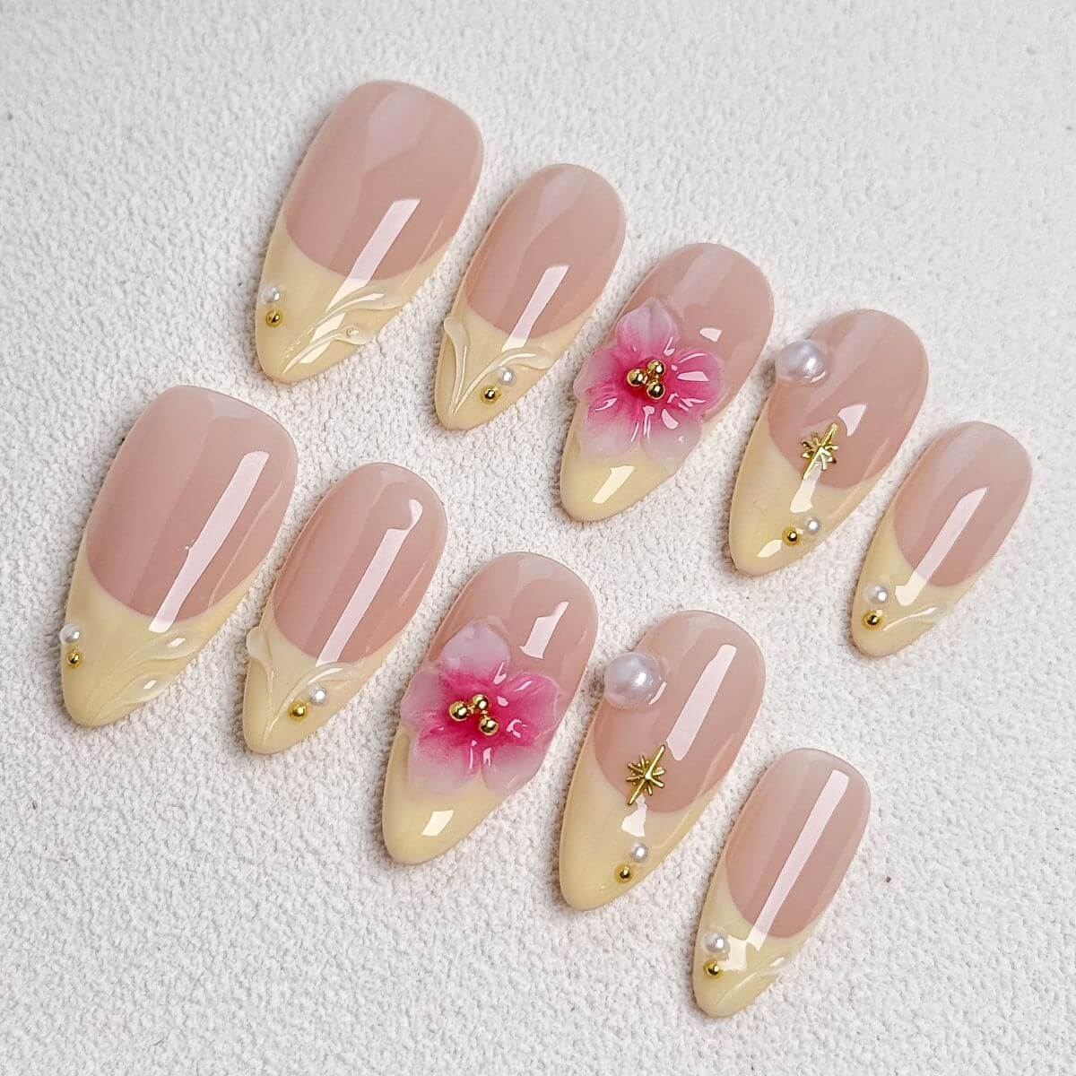 A product overview flat lay of the Vanilla Blossom artificial nail set, displaying 10 sample nails with pastel yellow French tips, 3D pink cherry blossoms, pearls, and gold stars.