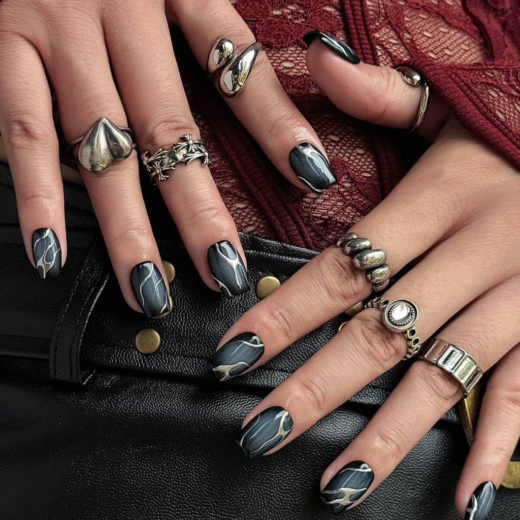 short coffin press-on nails with a smoky semi-translucent black quartz base and organic metallic silver flame-like liquid lines.