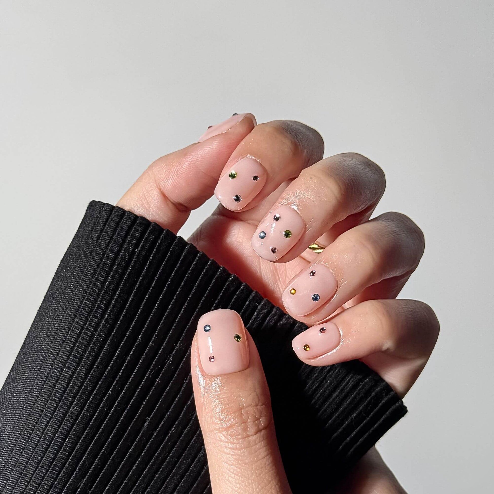 Lifestyle photo of a professional manicure featuring the Prism Petal handmade press-on nails, showcasing the elegant nude shimmer and short square shape.