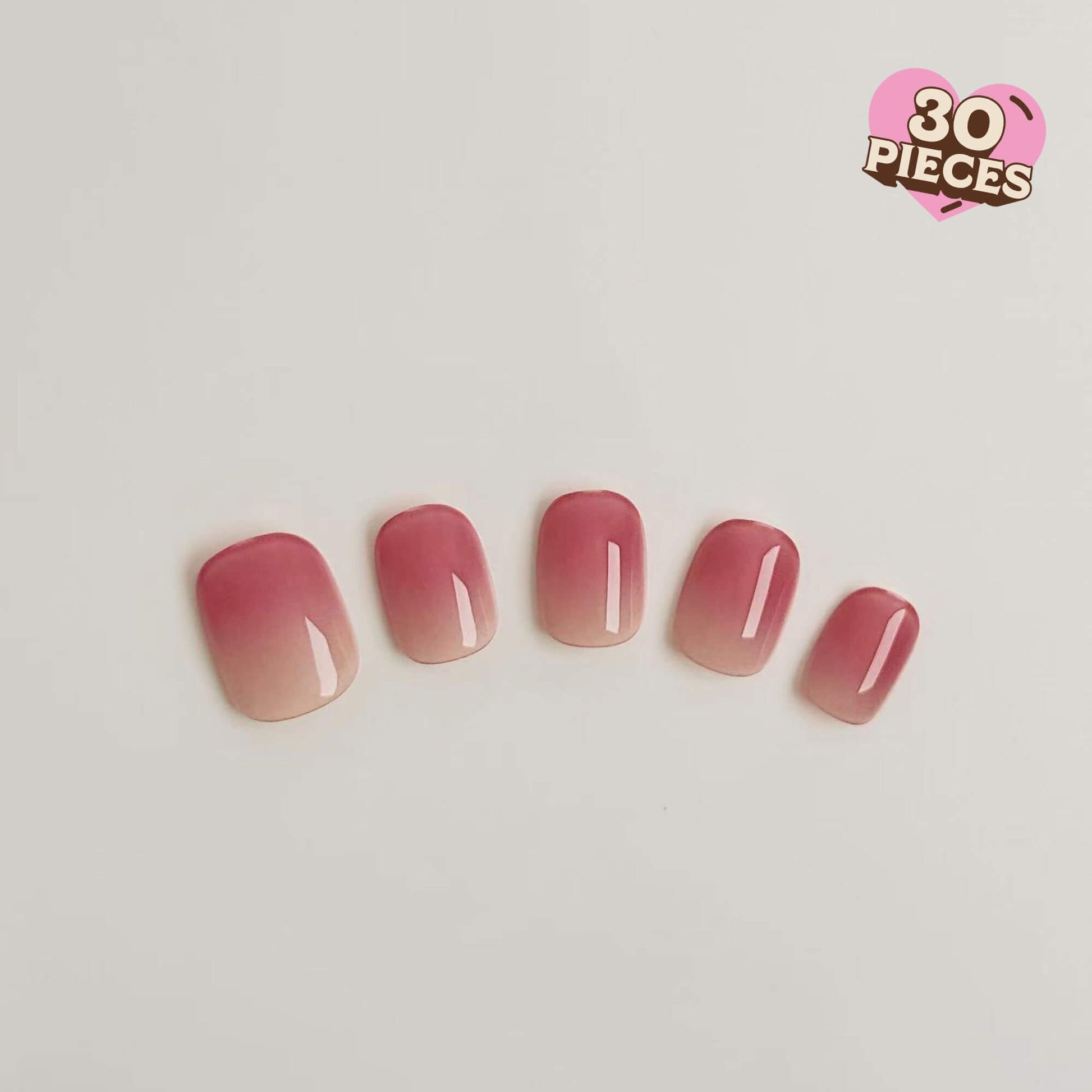 Eine Nahaufnahme von fünf Justmee Press-on-Nägeln mit einem weichen Farbverlauf von Rosé zu Nude, kurze runde Form mit glänzendem Finish.