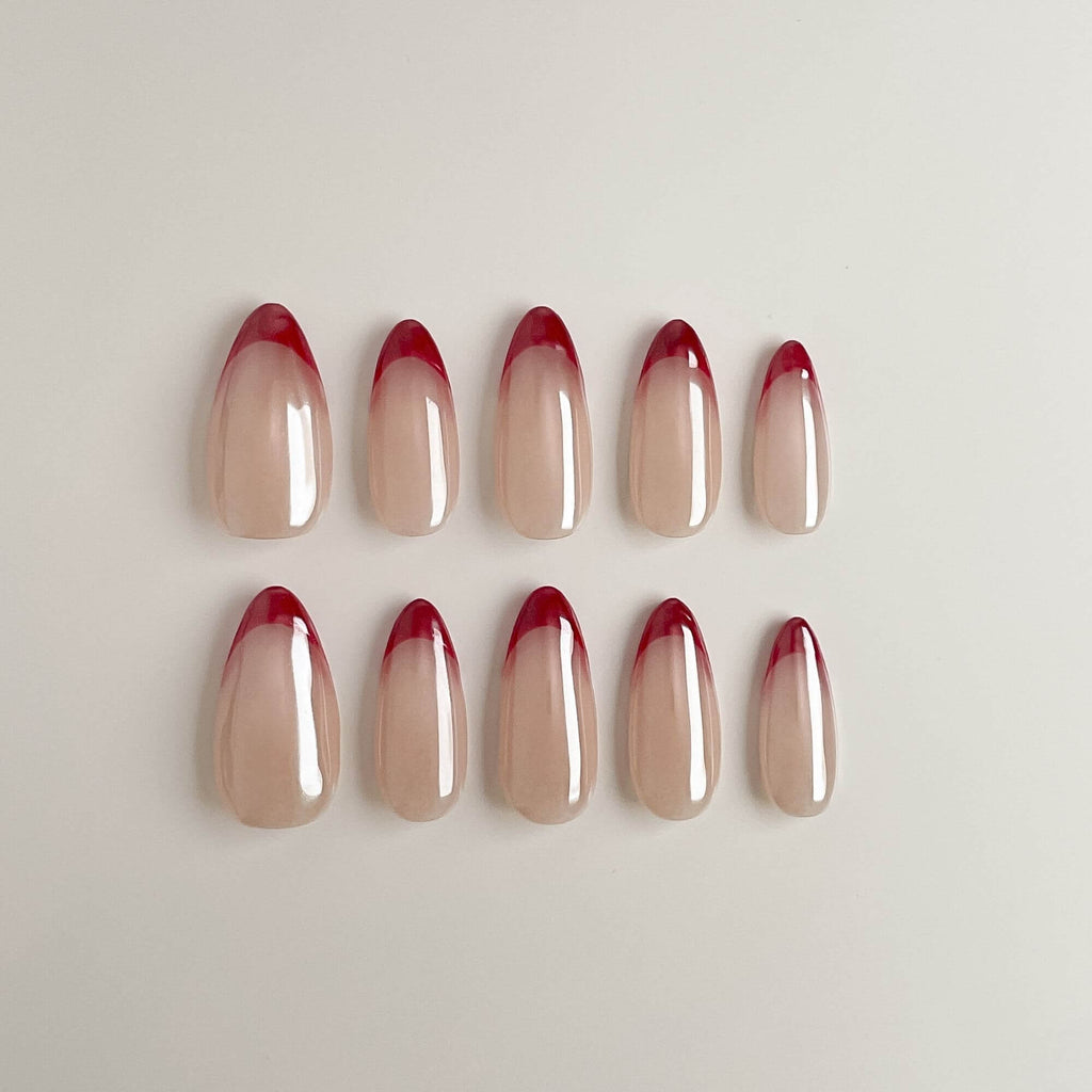 Ein 10er-Set handgefertigte Press-on Nails in Mandelform mit zarter Perlmutt-Chrome-Basis und klassischen roten French-Tips.