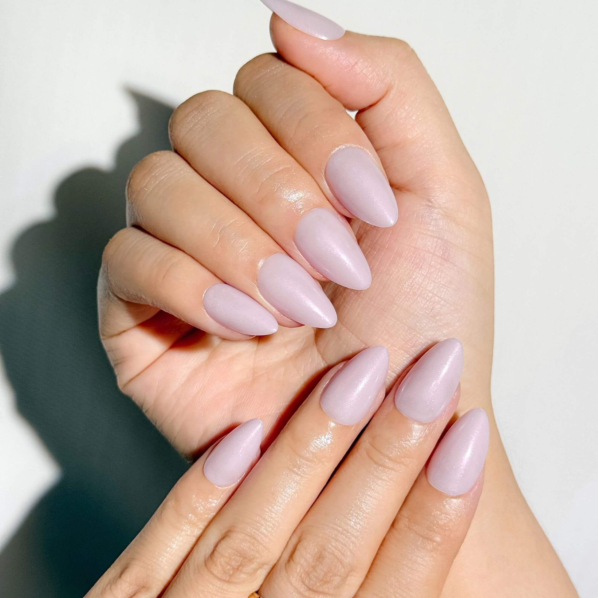 Nahaufnahme einer Hand mit silbernen magnetischen Nägeln in Mandelform, die das leuchtende Samt-Finish und den trendigen Cat-Eye-Glanz zeigt.