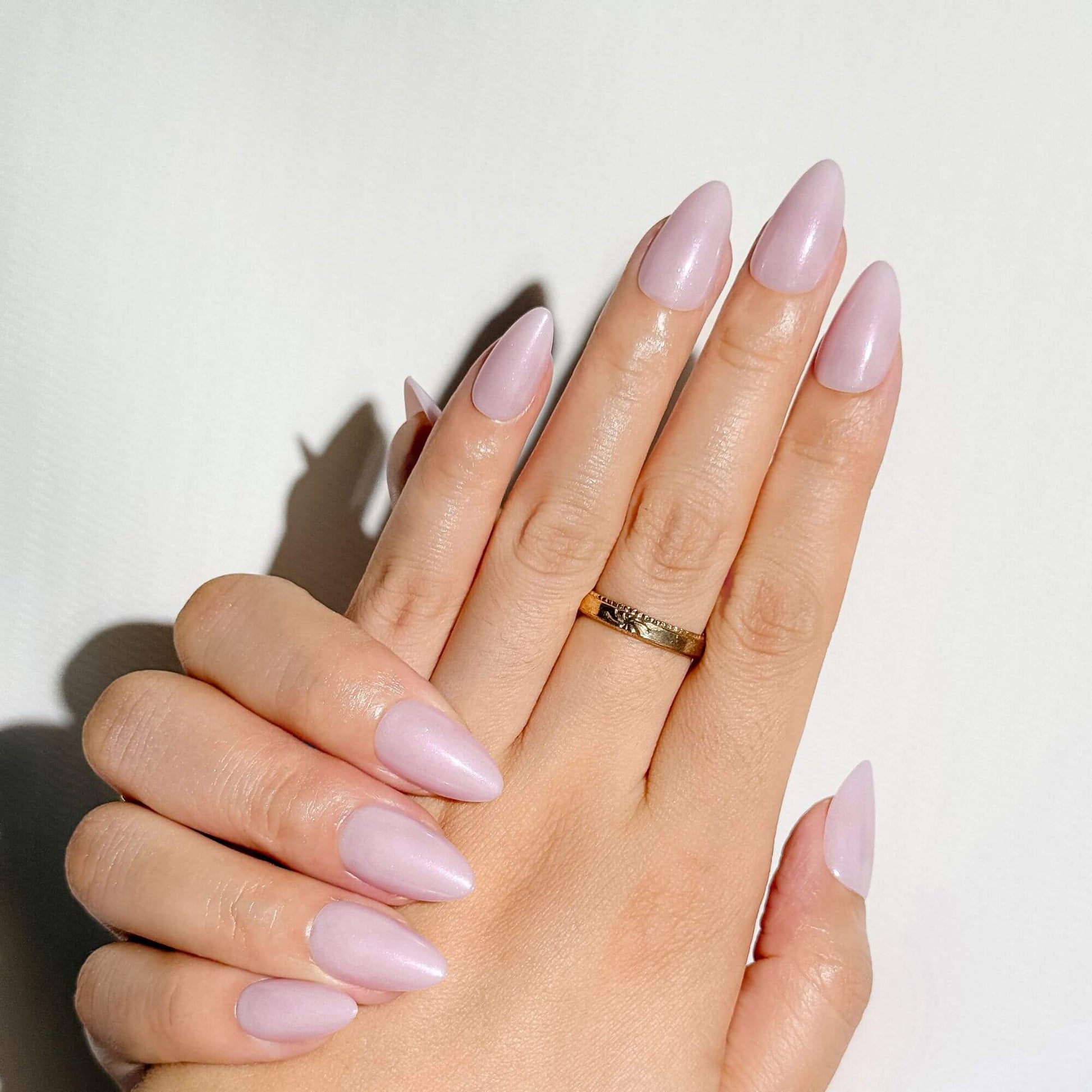 A pair of hands showcasing a full set of silver holographic magnetic almond nails, creating a futuristic and elegant manicure look.