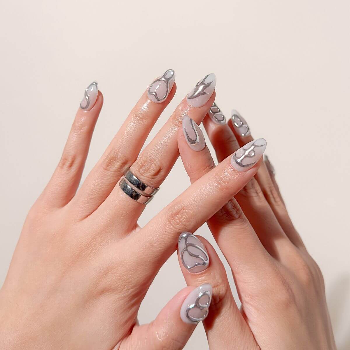 Close-up of minimalist fake nails by justmee worn on hands. Showcases organic silver chrome linework and 3D gel textures for a professional-grade manicure look.