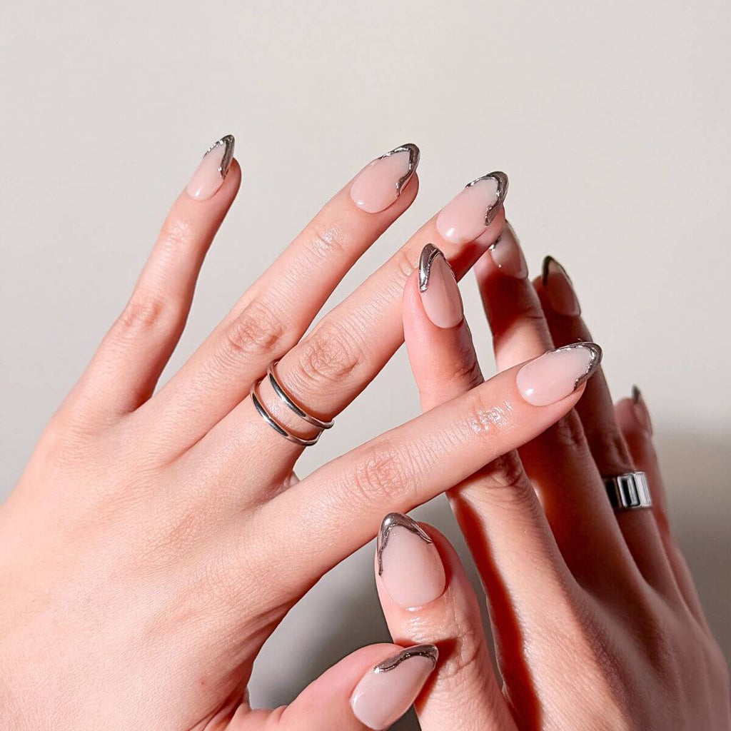 Close-up of The Chrome French fake nails by justmee worn on hands. Highlights the 3D liquid metal drip effect for a modern DIY manicure.