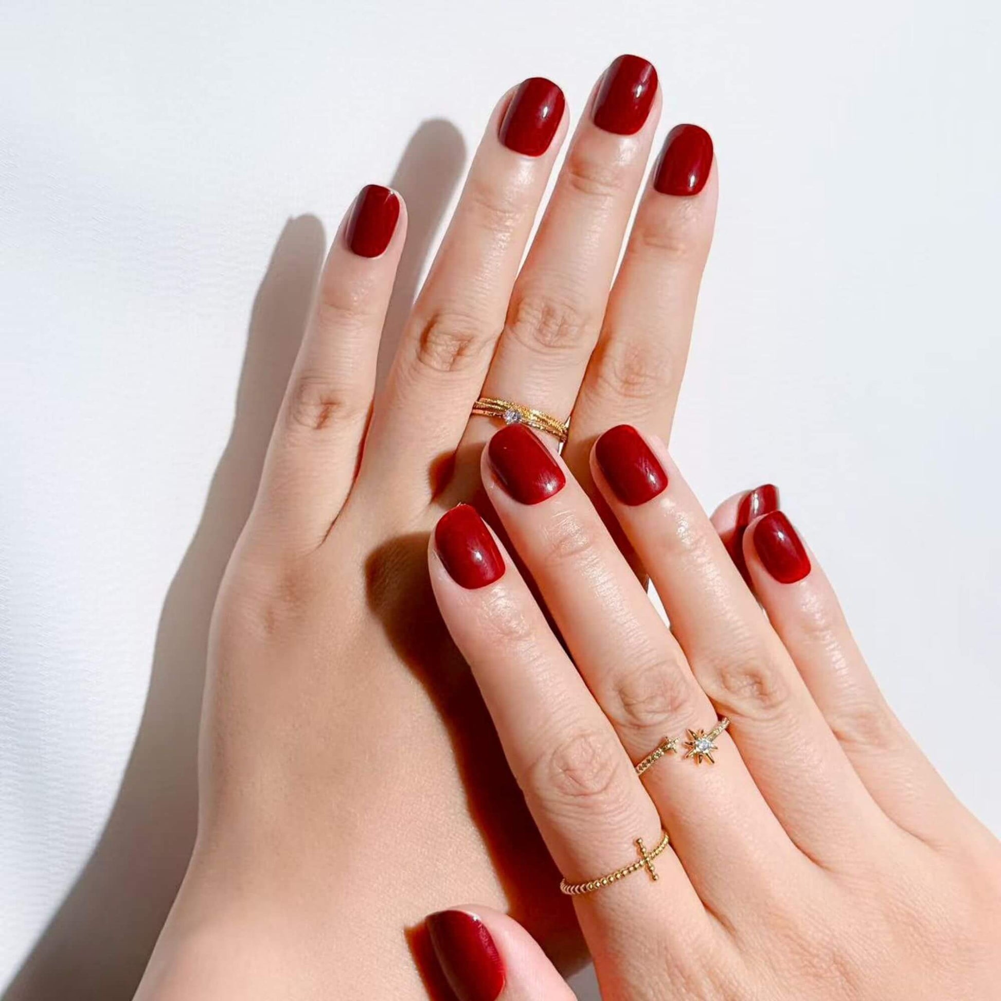 Elegant hands wearing Justmee wine red short press-on nails, showcasing a perfect fit and a classic, sophisticated manicure look.