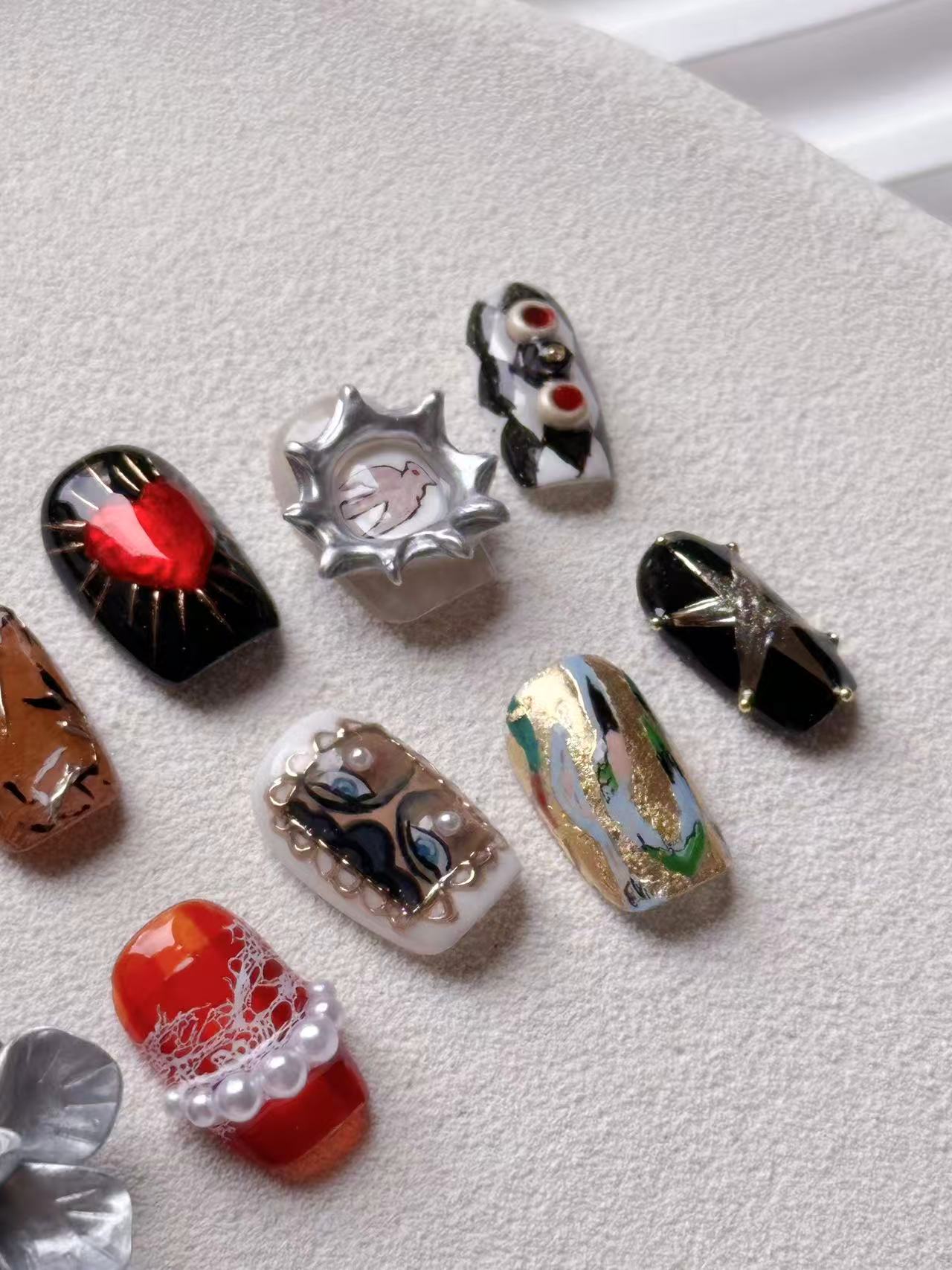 Detailed view of press-on nails with 3D pearl strings, gold foil marble, and a metallic star on black gel.