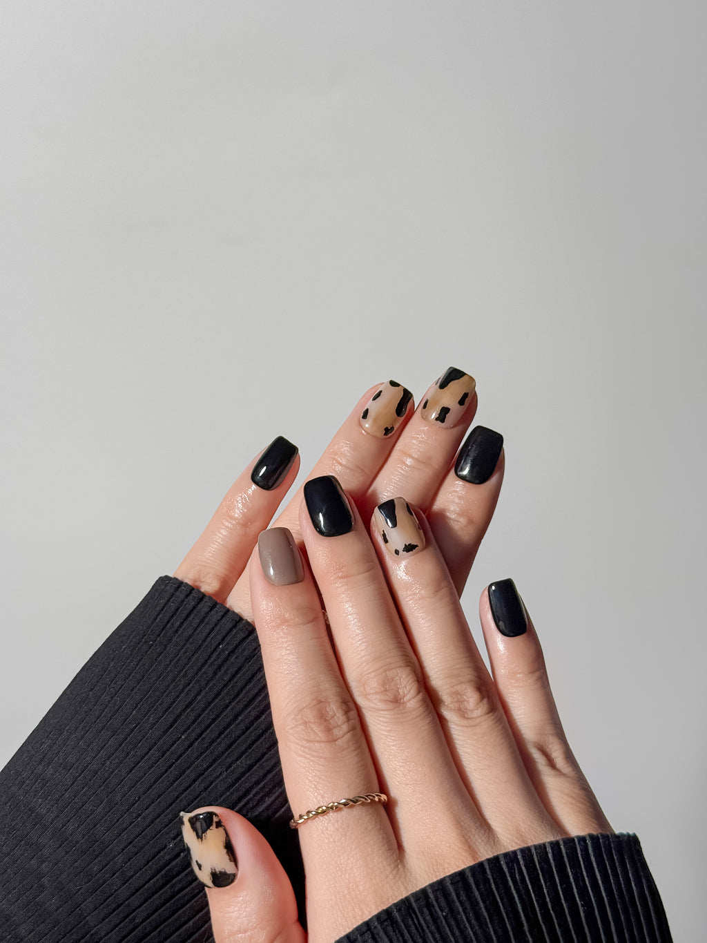 A trendy mix-and-match manicure featuring cow print and neutral earth tones on short square press-on nails.
