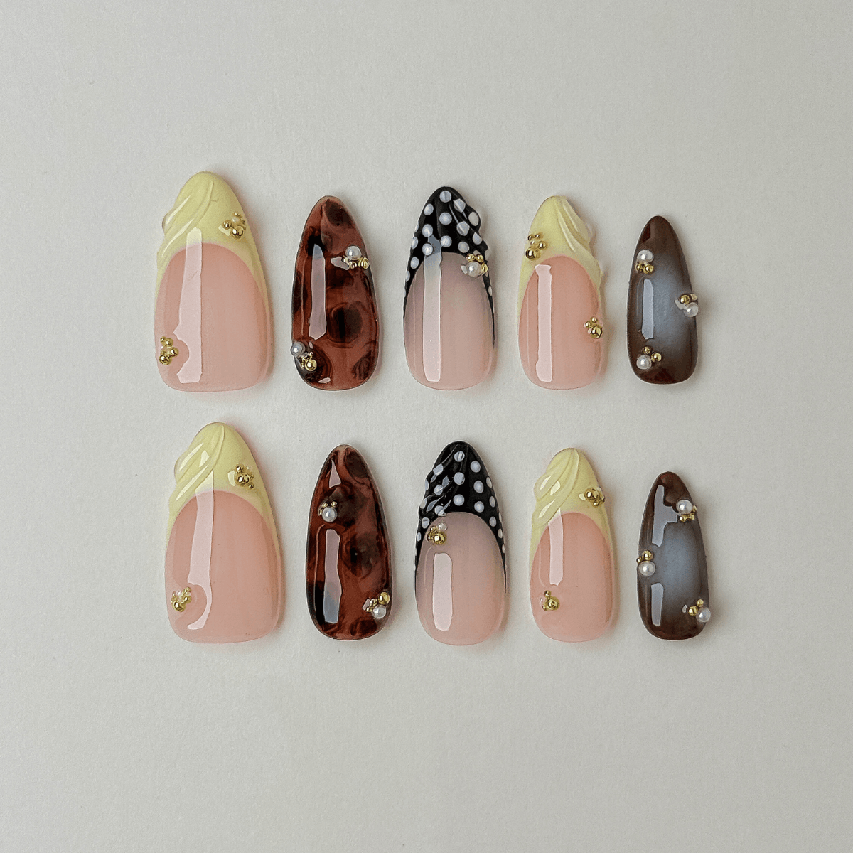 Handgemachte Press-On Nägel in Mandelform mit gelber 3D-Muschelstruktur, Schildpatt-Optik, french Punkte und Goldperlen.