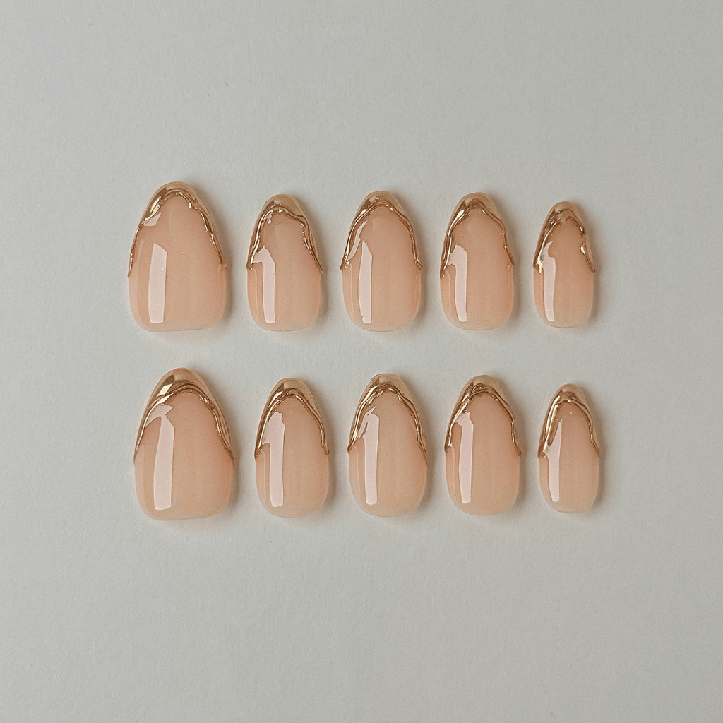Handgemachte Press-On Nägel in Nude mit 3D Gold-Chrome French-Spitzen in geschwungener Mandelform.