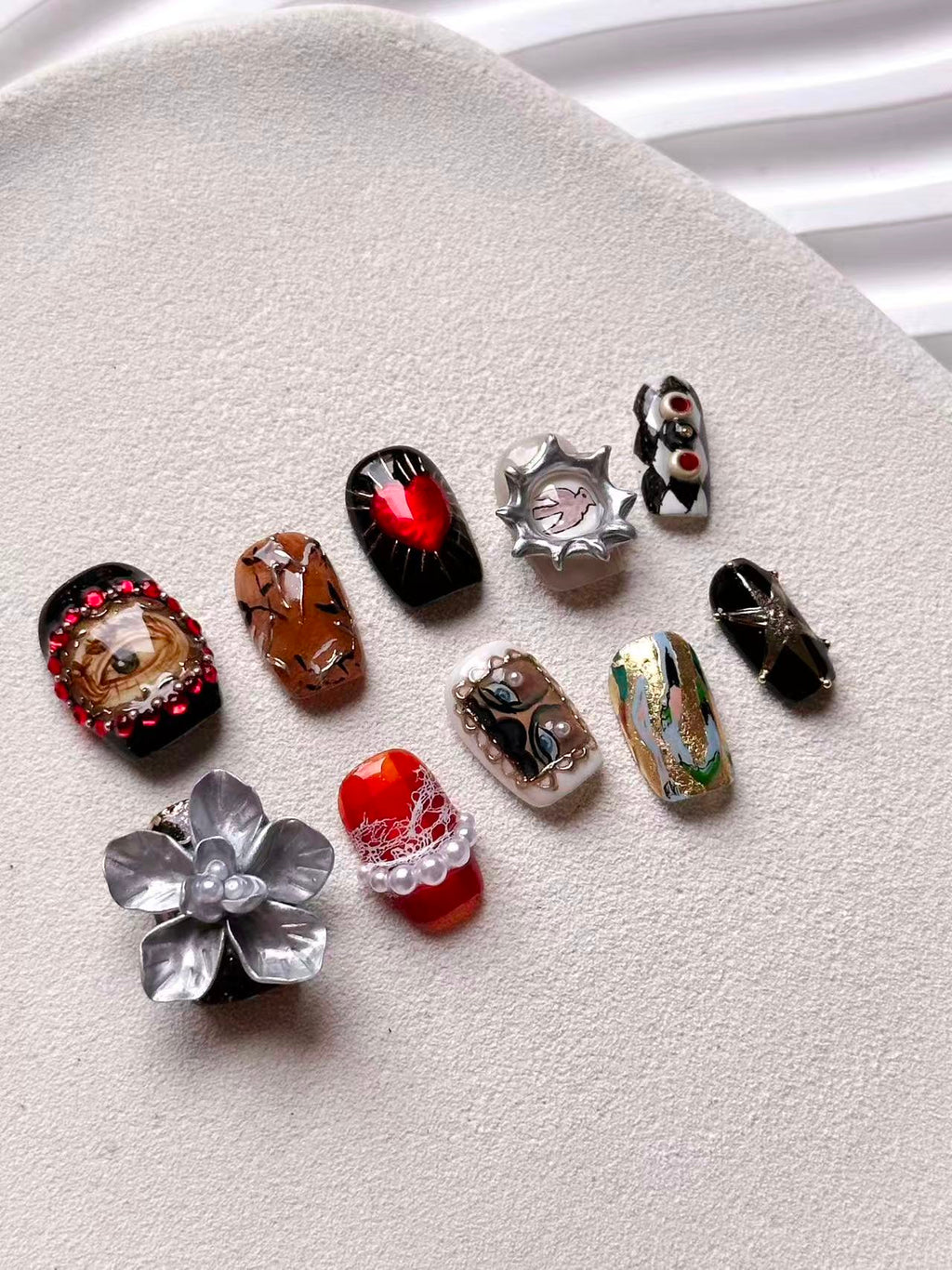 Luxury surrealist press-on nails featuring sacred heart, realistic eye, and 3D silver flower designs.