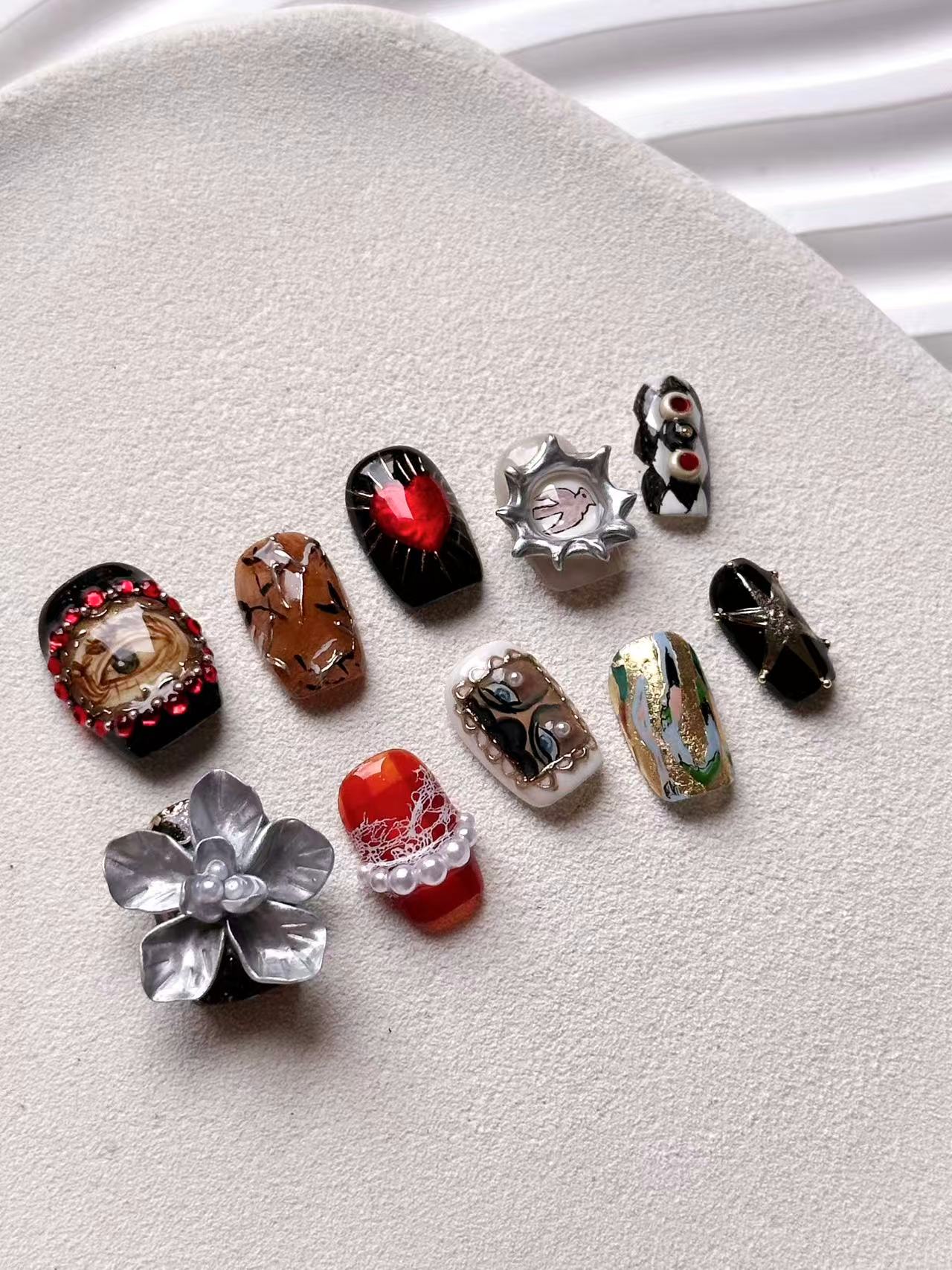 Luxury surrealist press-on nails featuring sacred heart, realistic eye, and 3D silver flower designs.