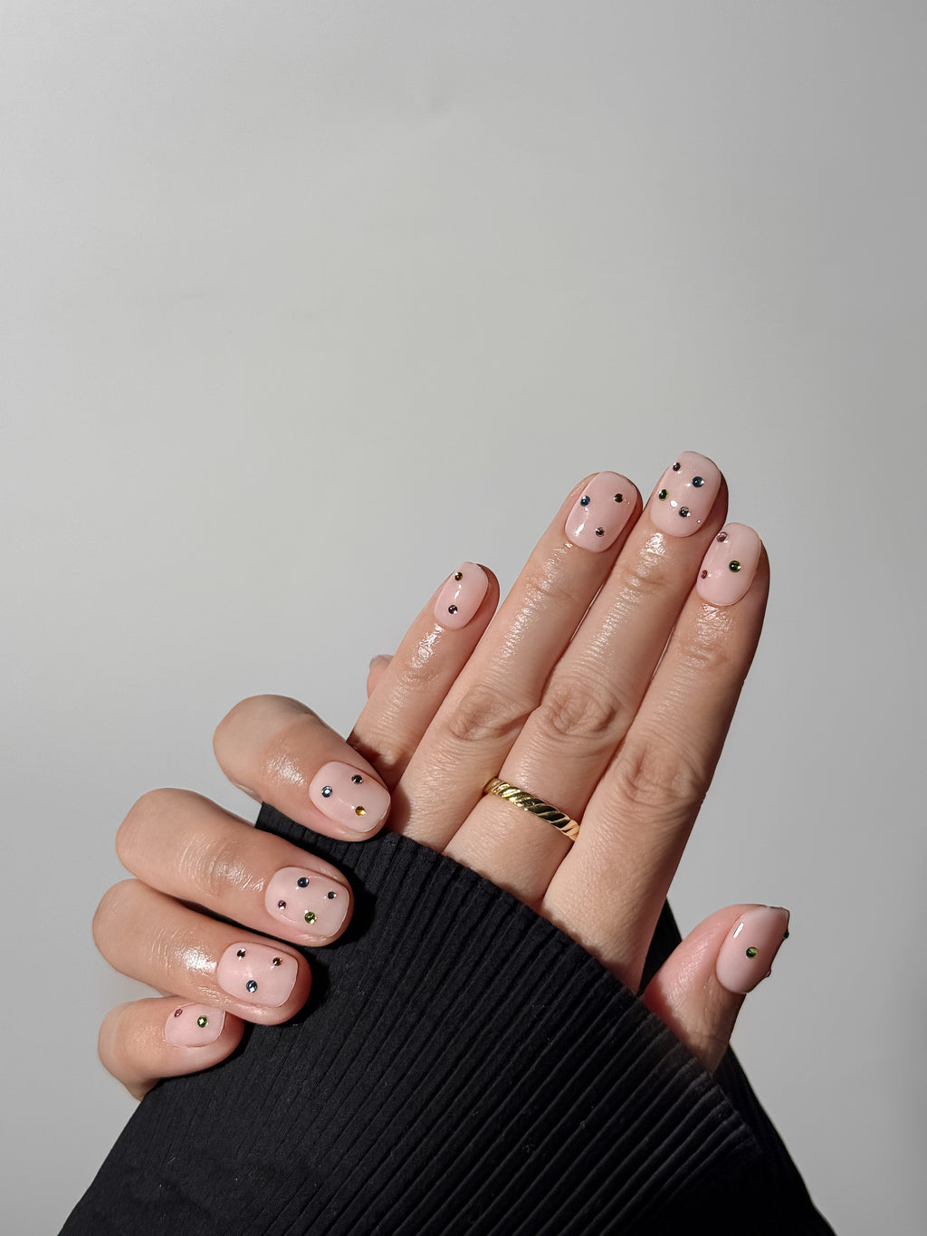 Model wearing Twinkle Pop pink press-on nails with multicolored crystals