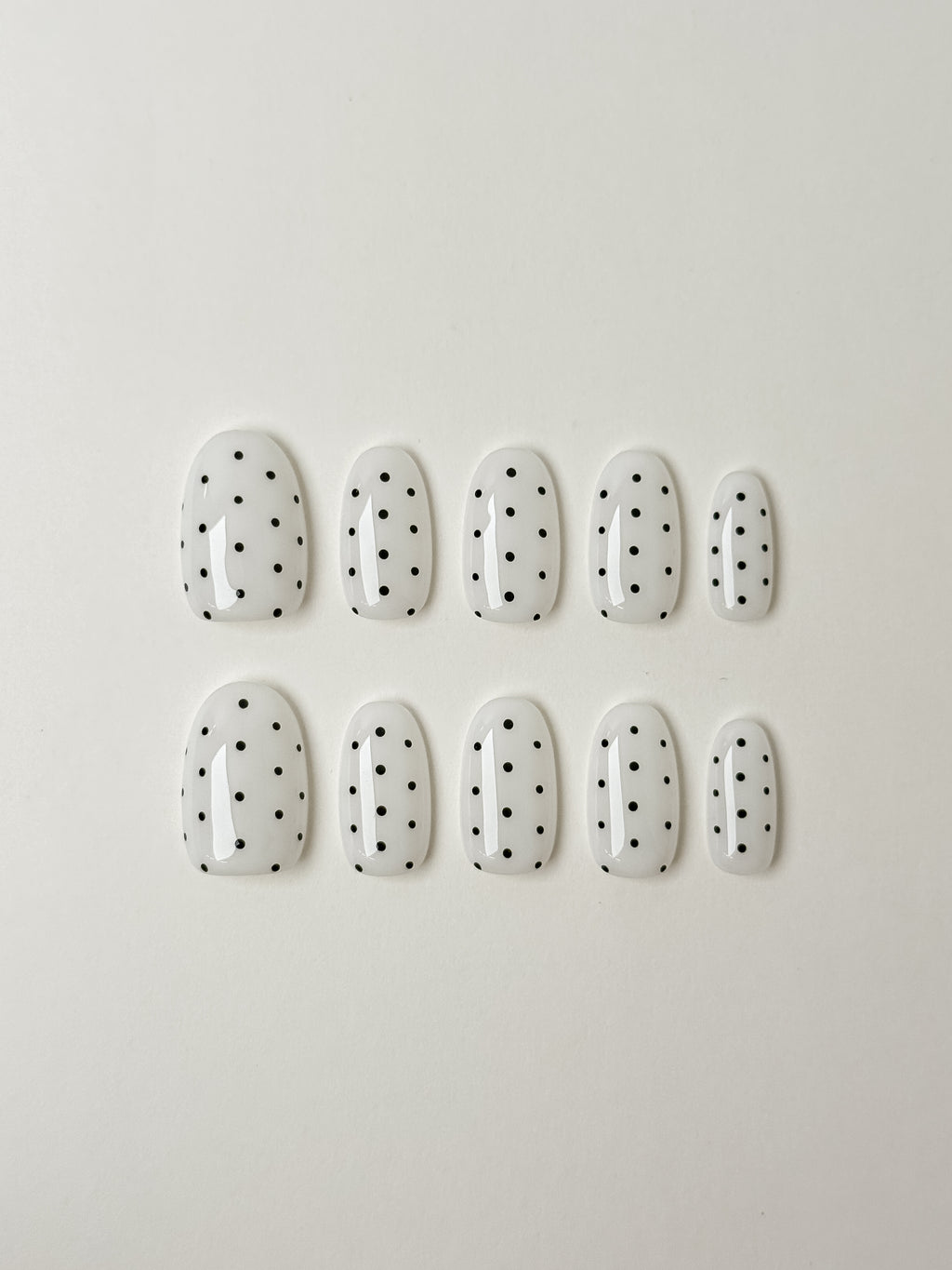 justmee press on nails in almond shape that are white with black dots. reusable and trendy styles